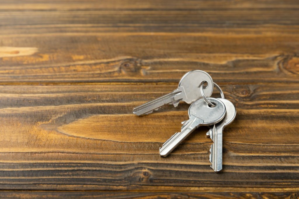 New door lock on a brown wooden background. Patent and keys to the front door. Contact tumbler of the internal mechanism of the cylinder lock and a set of keys. Real estate concept