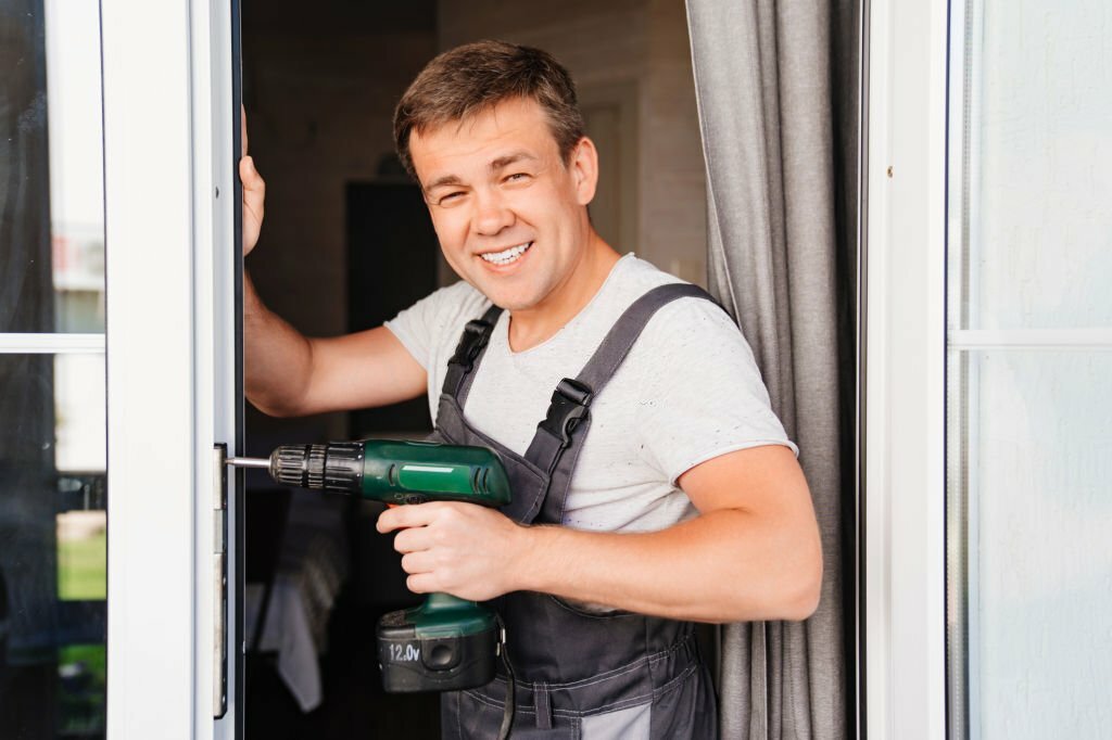 A repairman repairs or adjusts window frames or glass doors on the terrace. services of a repairman or installer of furniture and doors.