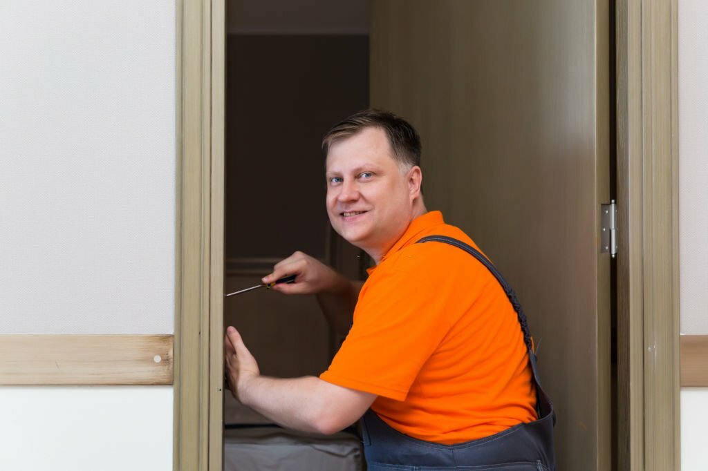 A man is installing a lock on the interior door of an apartment.